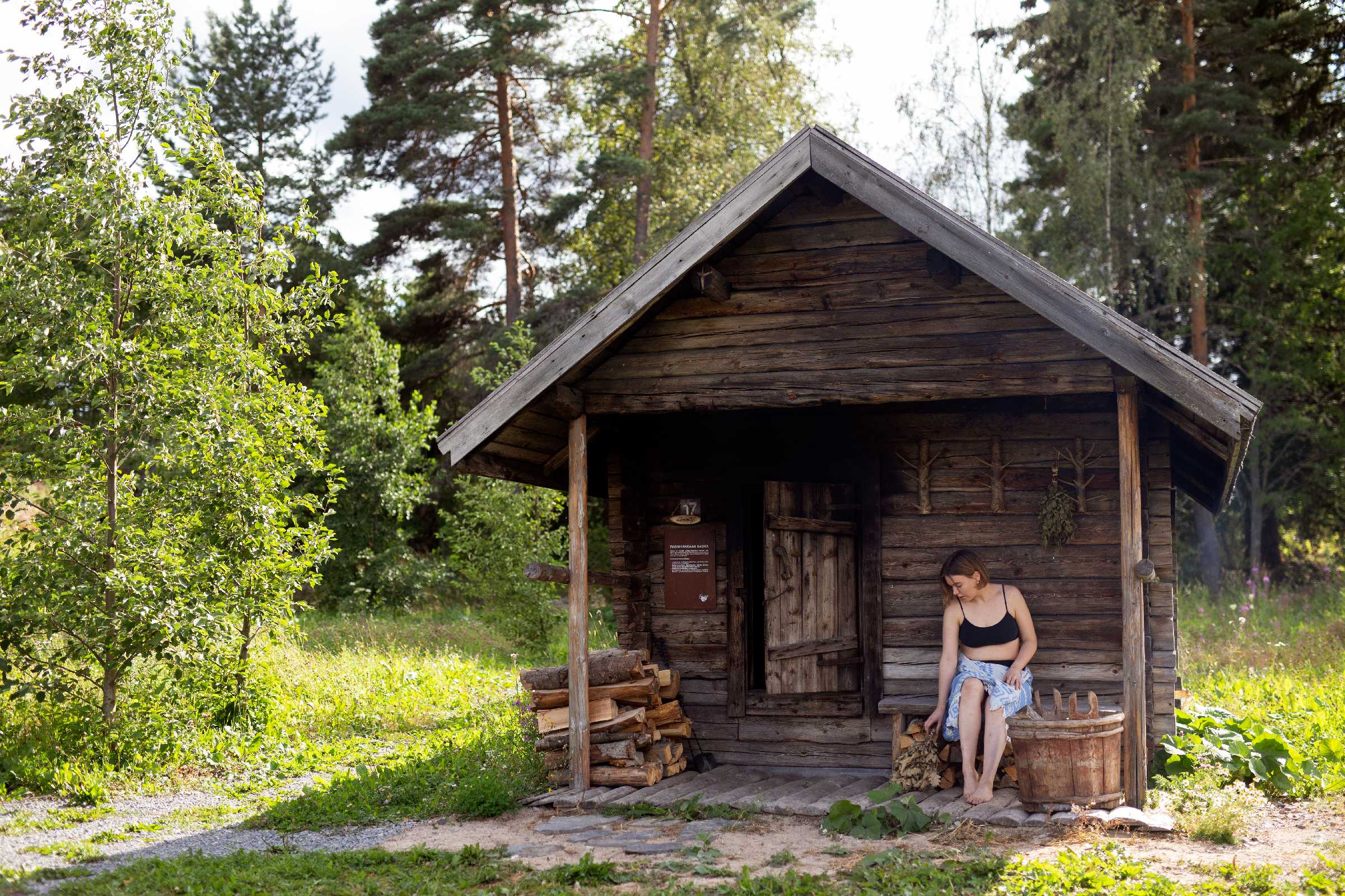 Nainen istuu savusaunan edessä